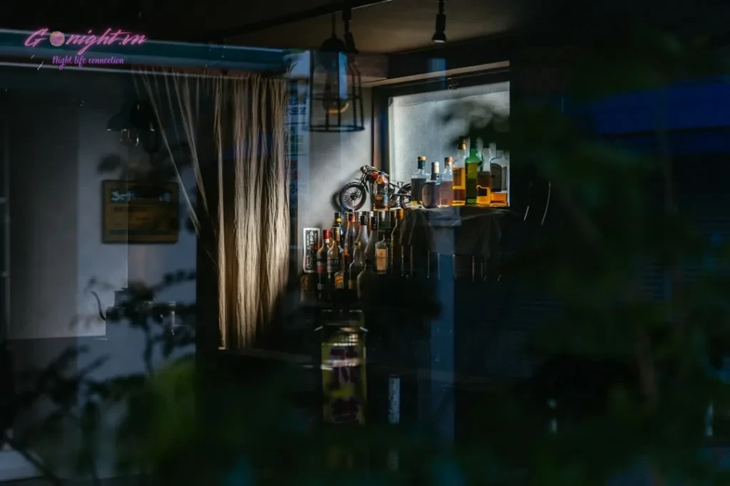 Cozy bar interior with bottles and lighting.