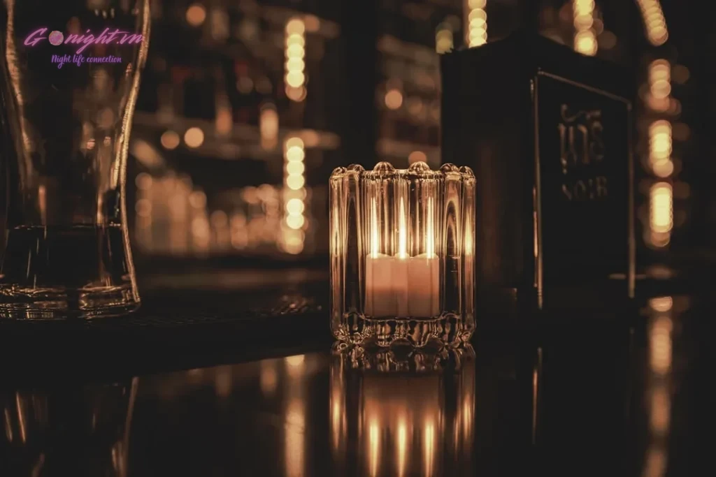 Candle lit in a glass holder on a bar counter.