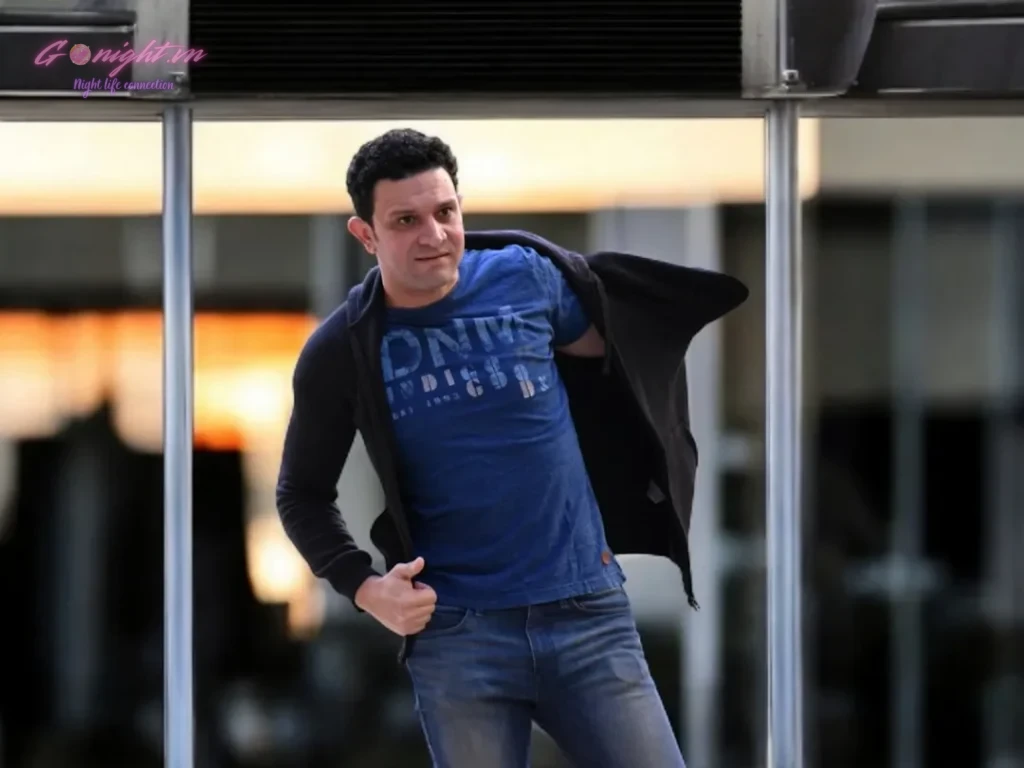 A man in a blue shirt and jeans standing on a skateboard