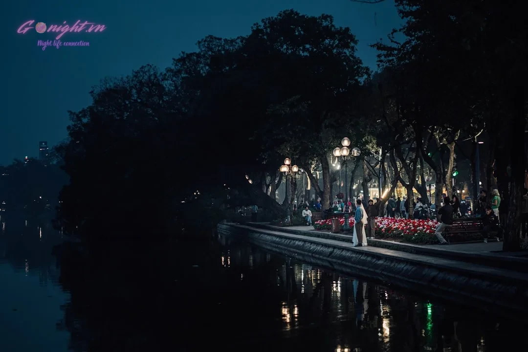 Hanoi's Heartbeat After Dark: An Insider's Guide to the Best Bars & Clubs in the Old Quarter 1 a person standing on the edge of a body of water at night