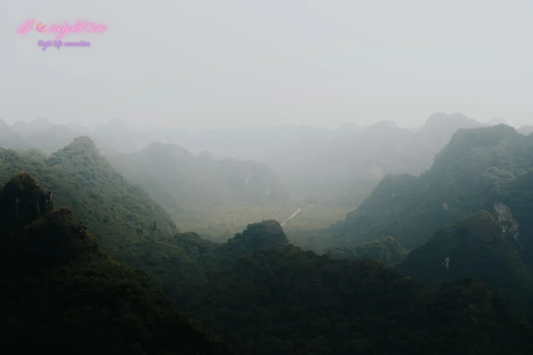 Green mountains fade into the misty horizon.
