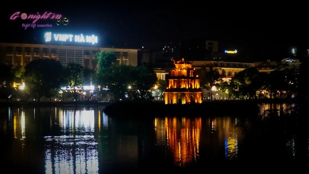Beyond the Old Quarter: A Guide to Exploring Hanoi's Diverse Nightlife Districts 13 Cityscape at night with illuminated temple and reflections.