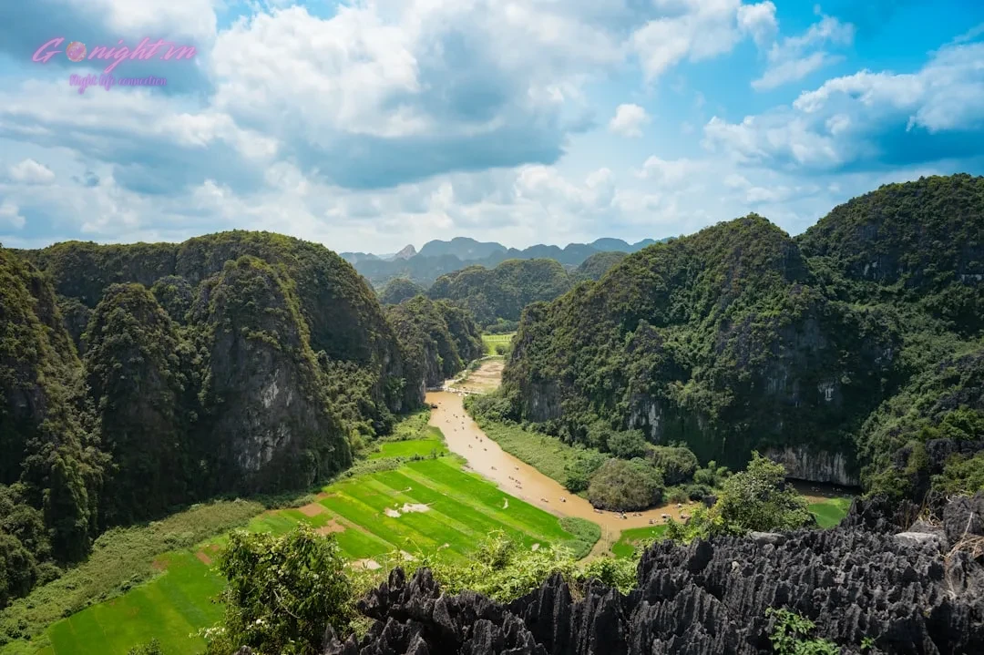 Lush green mountains surround a winding brown river.