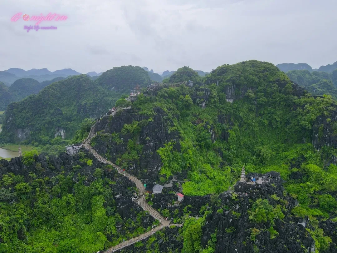 Lush green mountains with a winding path and scattered buildings.