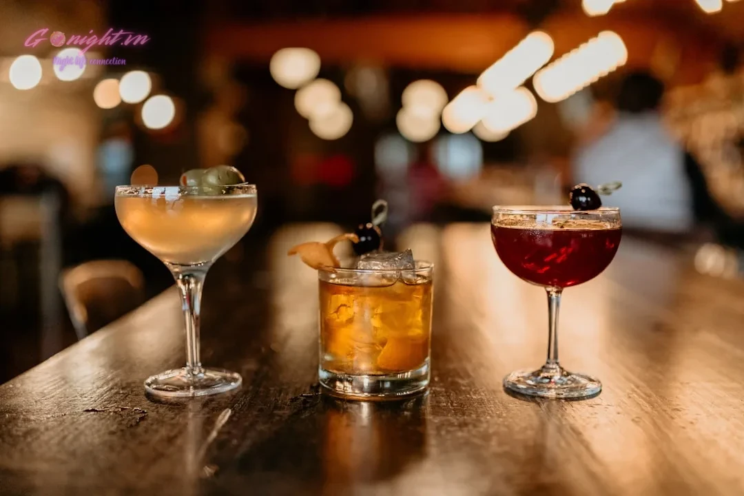 two glasses of different types of drinks on a bar
