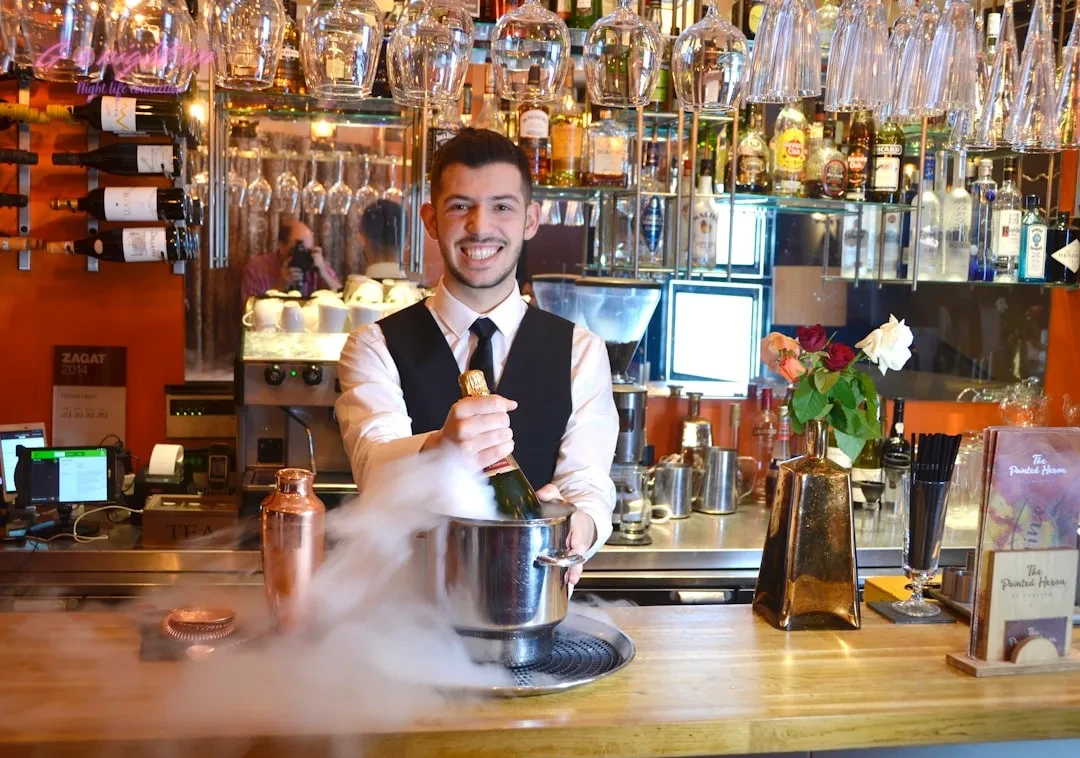 a person smiling and holding a silver teapot