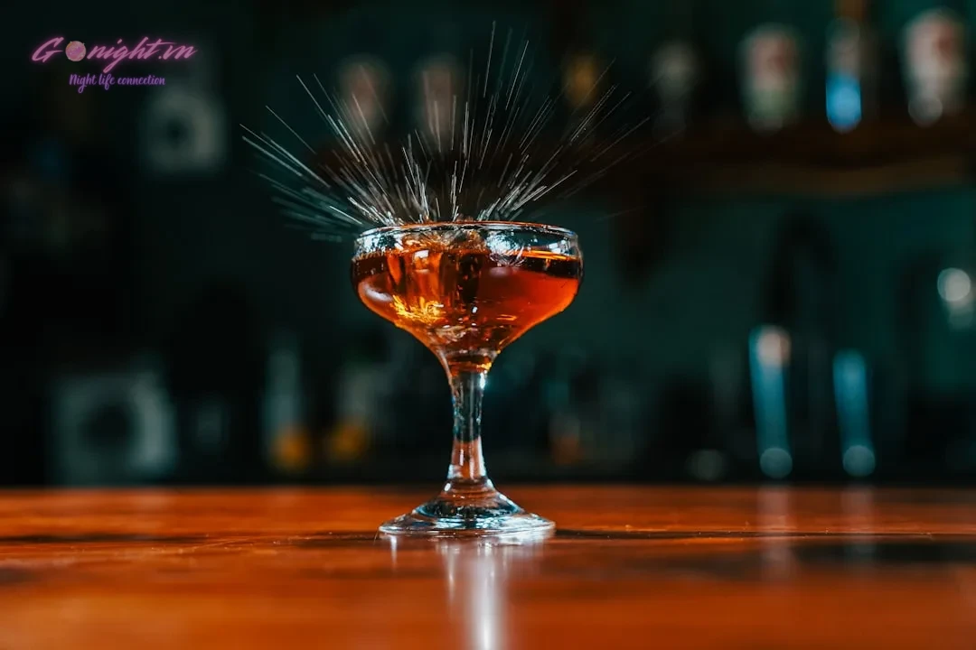 A glass of alcohol sitting on top of a wooden table
