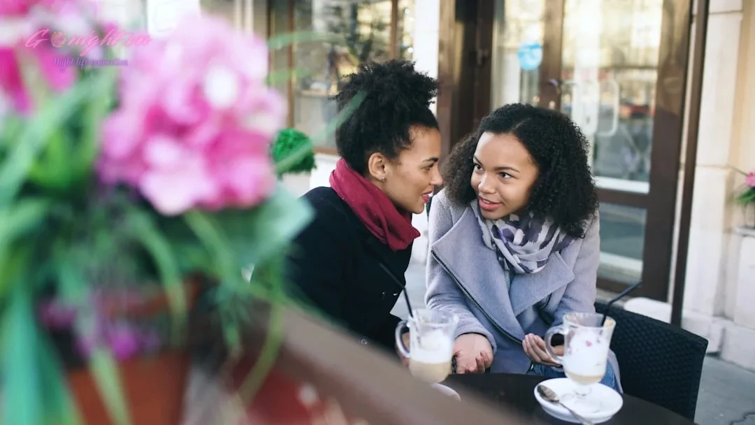 Two women talking at an outdoor cafe table.