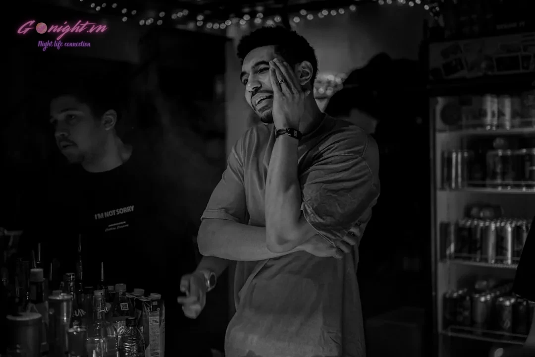 A man smiles, looking upward, at a bar.