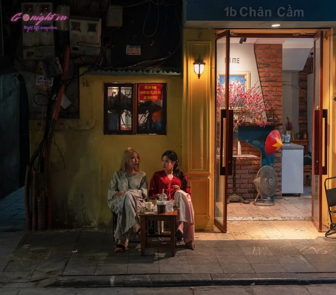 Hanoi's Secret Sips: Top 7 Hidden Speakeasy & Unique Concept Bars in Ba Dinh and Hoan Kiem 9 Two women sit at a small table outside a cafe.