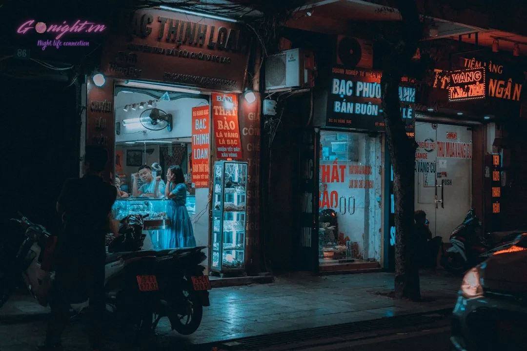 A dark city street at night with people walking by
