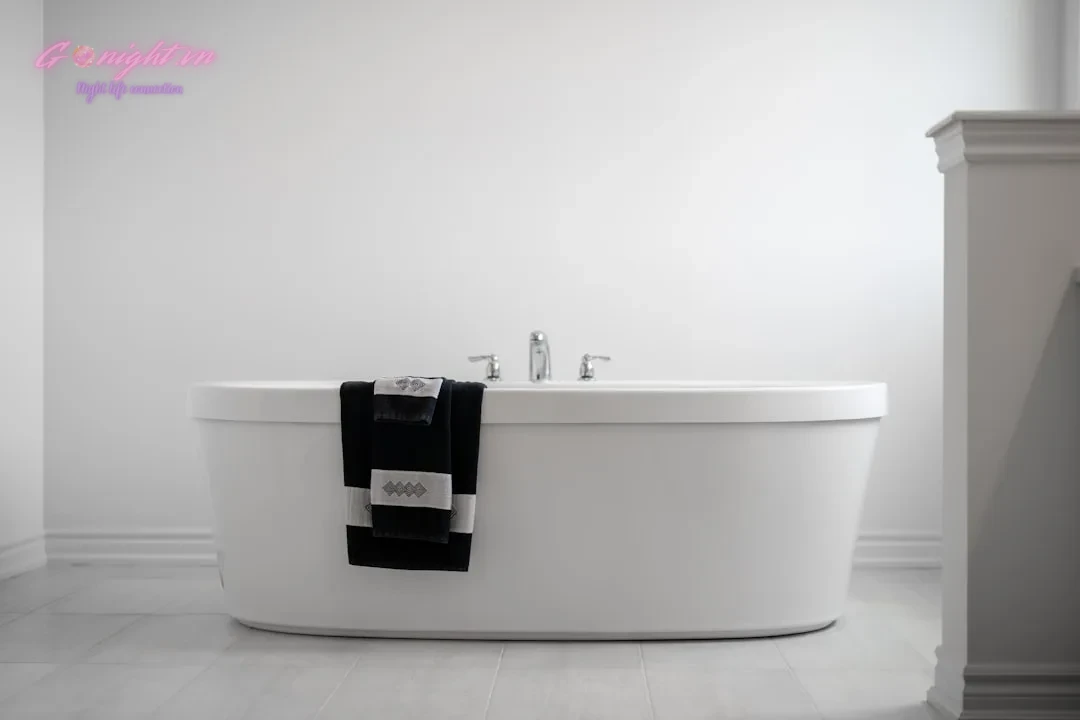 A modern bathtub with towels draped over the side.