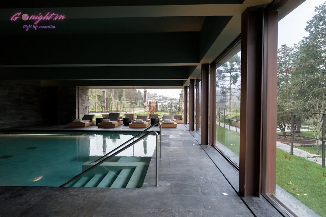 Top 7 Luxury Massage & Spa Centers in Binh Chanh: Ultimate Relaxation Escapes 1 Indoor swimming pool with lounge chairs and large windows.