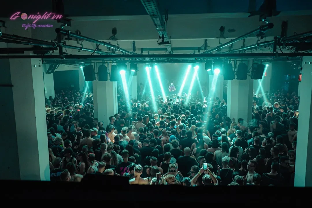 Crowd dancing under bright stage lights at concert