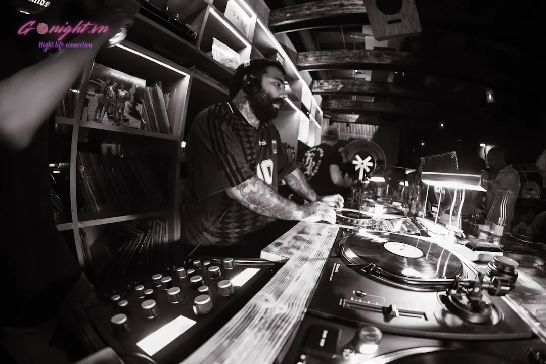 Dj performing at turntables in a dark club