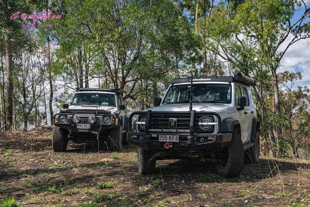 Two off-road vehicles parked in a wooded area.