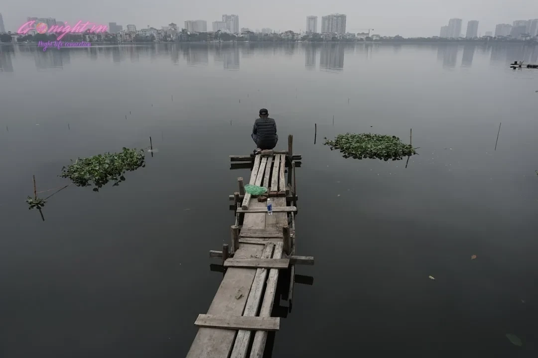 Beyond the Old Quarter: A Guide to Exploring Hanoi's Diverse Nightlife Districts 2 a man sitting on a wooden dock in the middle of a lake