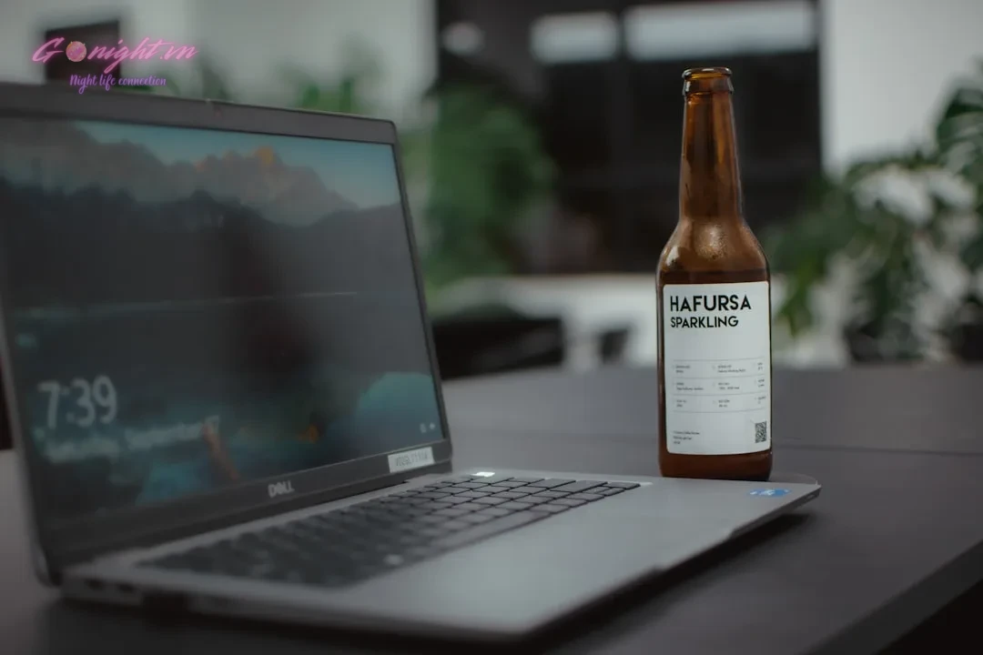 a bottle of beer next to a laptop
