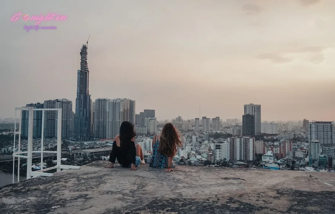 Ho Chi Minh City's Sky-High Escapes: Top 7 Rooftop Bars with Breathtaking Views 5 woman in black jacket sitting on gray concrete floor looking at city buildings during daytime