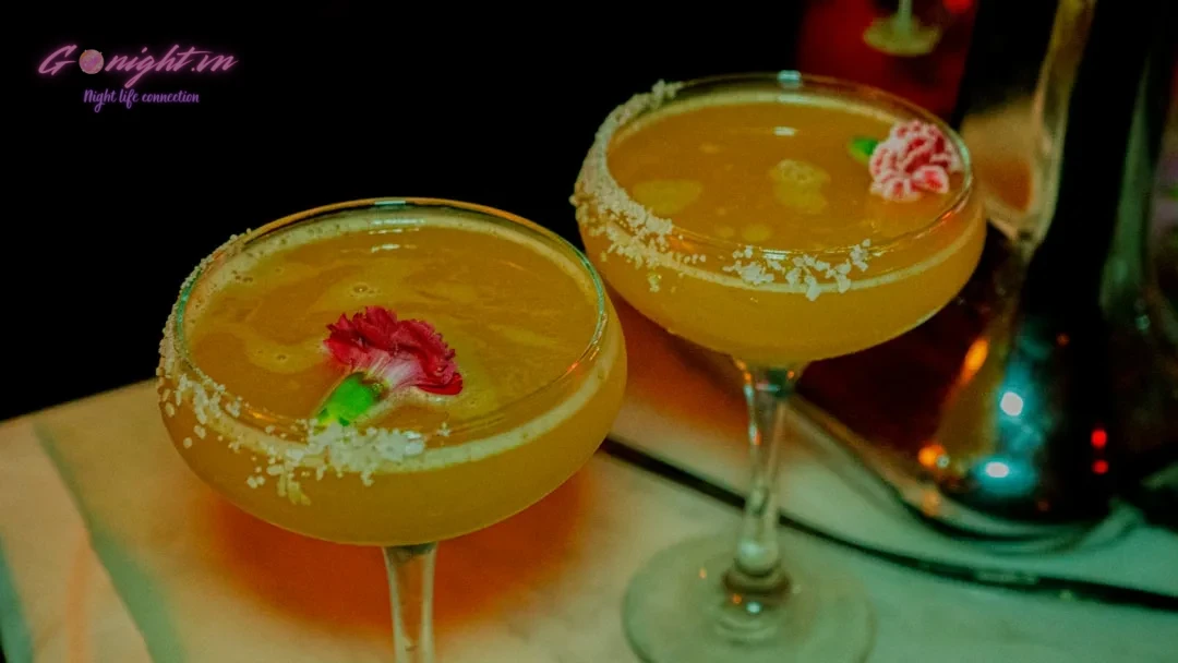 Two cocktails are served with a delicate garnish.