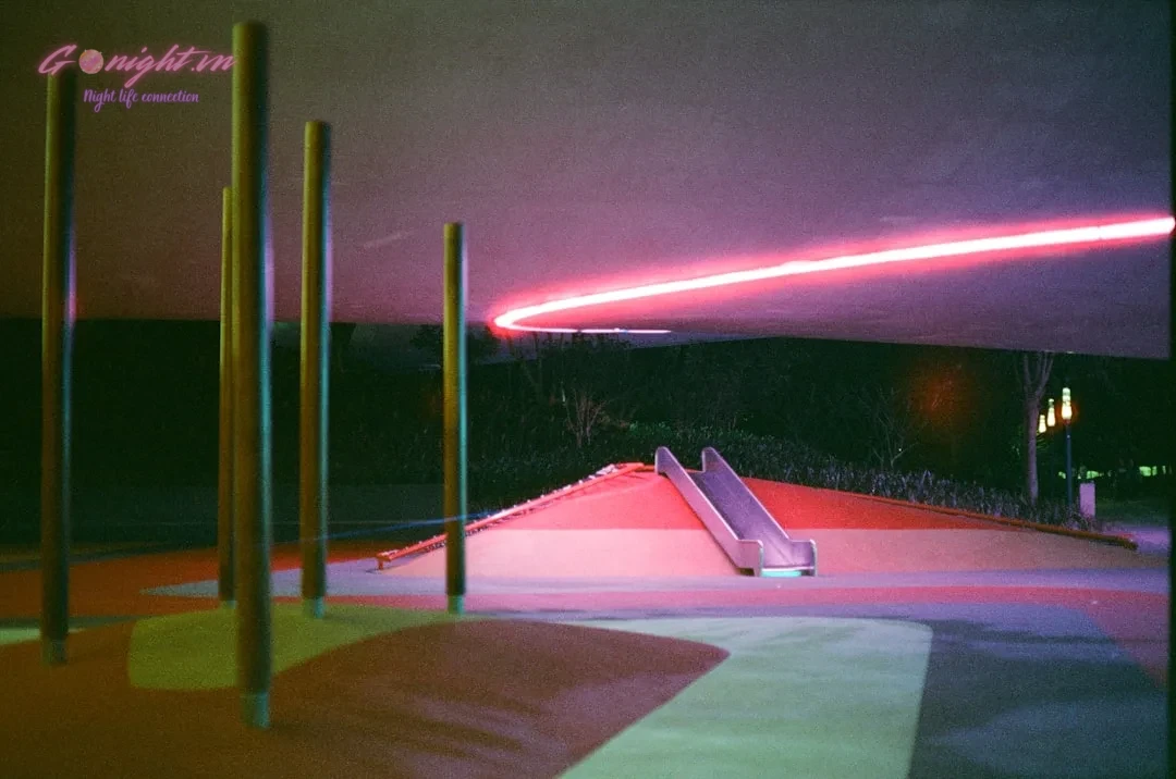 Neon light streaks across a modern urban landscape at night.