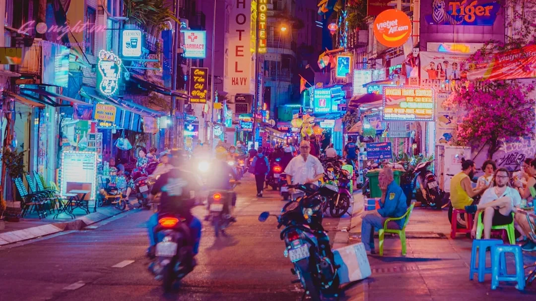 Ultimate Vietnam Travel Guide: Essential Tips and Nightlife Secrets 11 Neon-lit street with people and motorbikes at night.